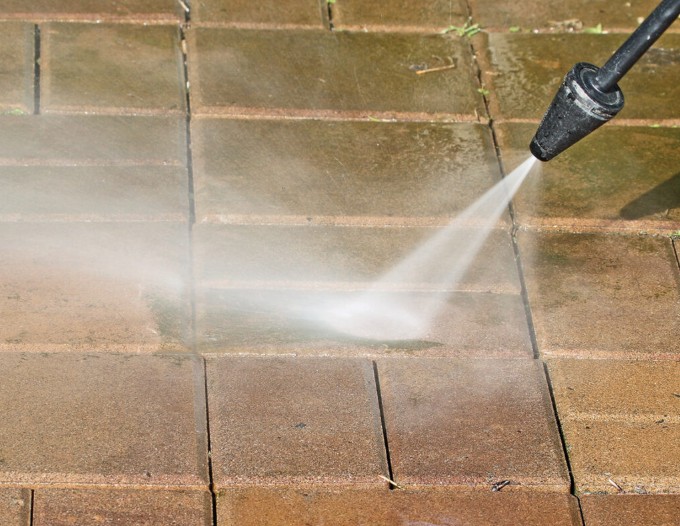 High-pressure power washing in action removing dirt and stains from paver surfaces