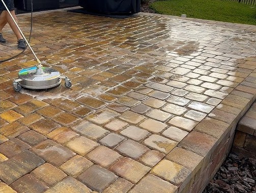 Professional power washing service cleaning large paver patio with specialized equipment