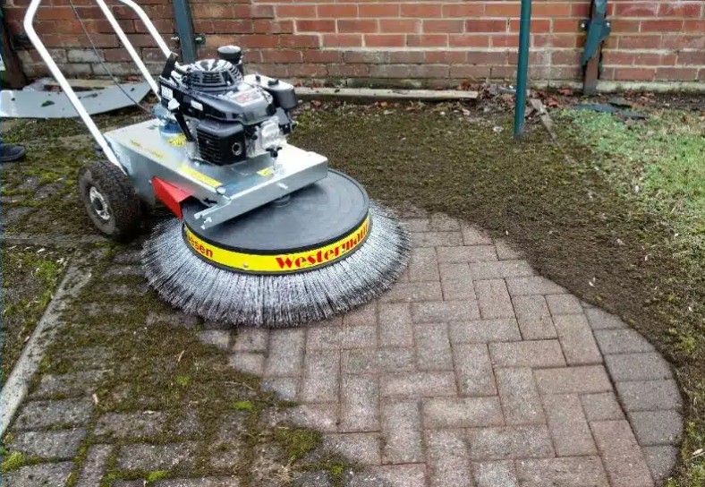 Rotary power scrubber with spinning brush cleaning paver driveway surfaces effectively