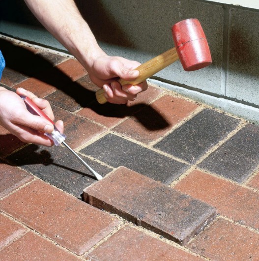 Professional hands-on paver repair work showing expert installation techniques and quality craftsmanship