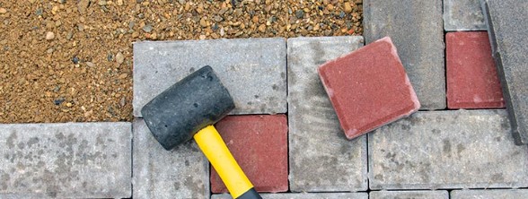 Professional paver repair tools including rubber mallet and replacement pavers for quality restoration work