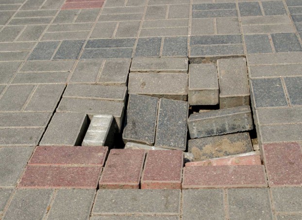 Severe paver damage with large holes and missing pavers requiring complete section restoration