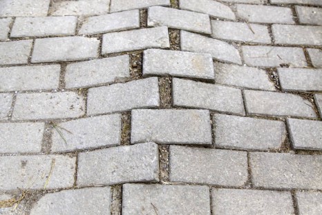 Dangerous uneven paver buckle creating significant height differences and safety hazards