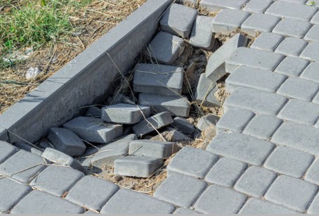 Dangerous paver trip hazard with large gaps and uneven surface requiring professional leveling