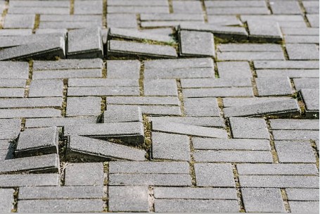 Uneven brick pavers creating dangerous trip hazards requiring immediate safety repairs
