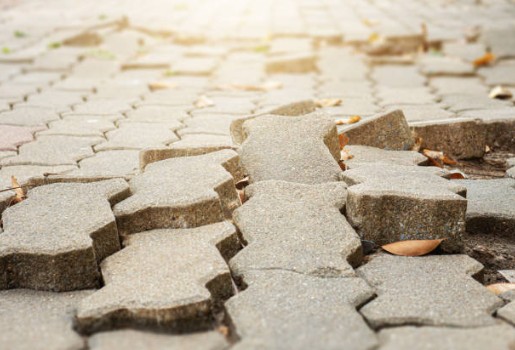 Multiple uneven pavers showing settling and base erosion requiring professional releveling
