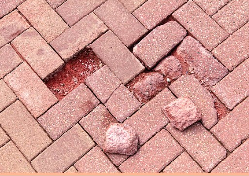 Worn and cracked brick pavers showing weathering damage and deterioration over time